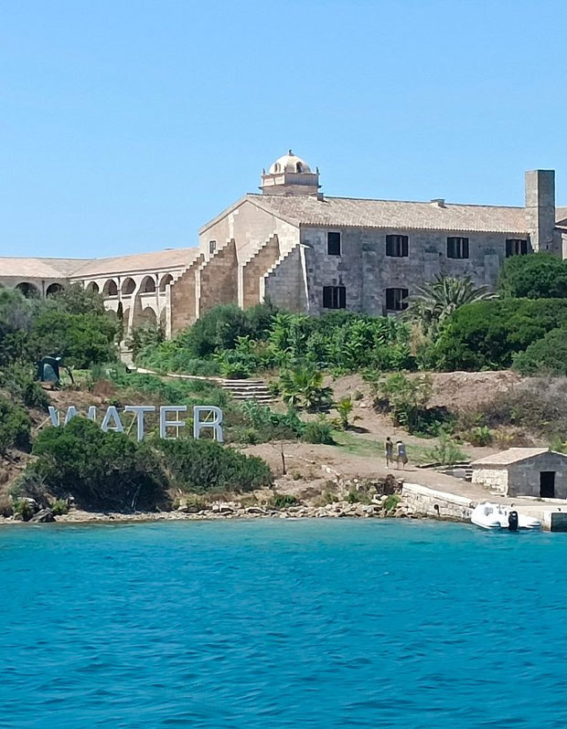 edificio en piedra, con vegetación cerca del mar